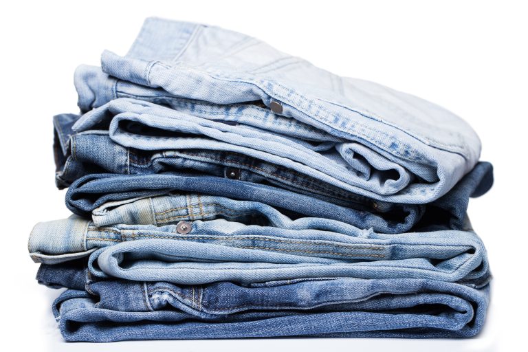 A pile of various pairs of jeans over a white background